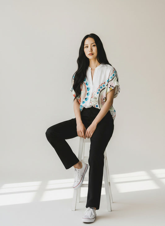 Magasin Dawo Bluse mit buntem Muster aus Baumwollmix, getragen von einem Model auf einem Hocker